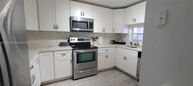 a kitchen with stainless steel appliances granite countertop white cabinets sink and stove