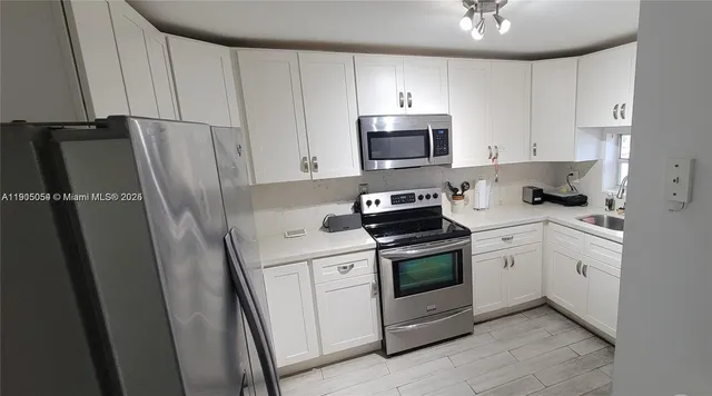 a kitchen with white cabinets sink and stainless steel appliances
