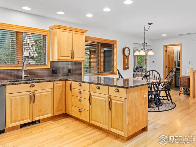 a very nice looking kitchen with granite countertop a stove a sink a dining table and chairs