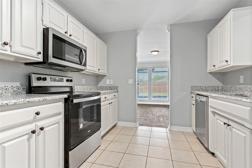 712 Billups Street Van Alstyne, TX 75495 - Photo 19 of 38 a kitchen with stainless steel appliances granite countertop a stove top oven microwave and cabinets