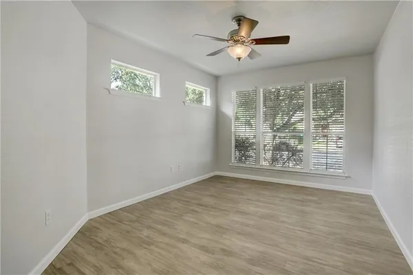 a view of an empty room with a window and a chandelier fan