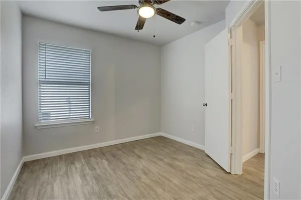 an empty room with wooden floor chandelier fan and windows