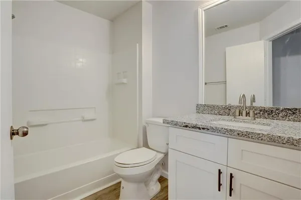 a bathroom with a granite countertop sink a toilet and bathtub