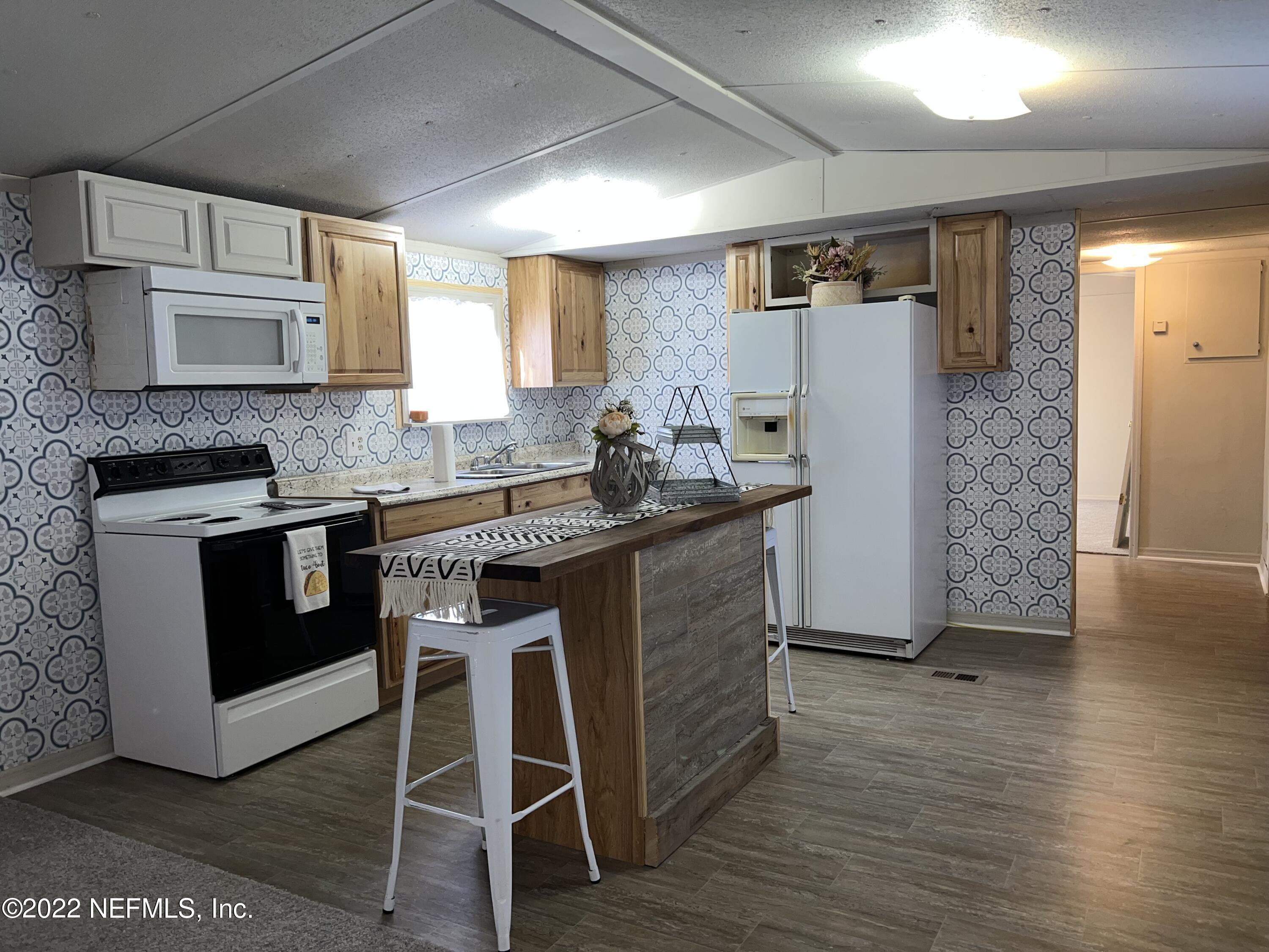 8008 Sunnybrook Road Melrose, FL 32666 - Photo 3 of 17 a kitchen with stainless steel appliances granite countertop a stove a refrigerator a sink and white cabinets with wooden floor