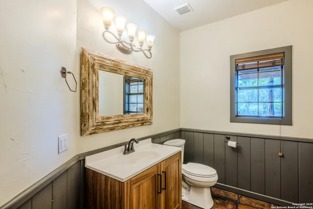 a bathroom with a toilet a sink a mirror and a window