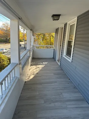 a view of an empty room with wooden floor and windows