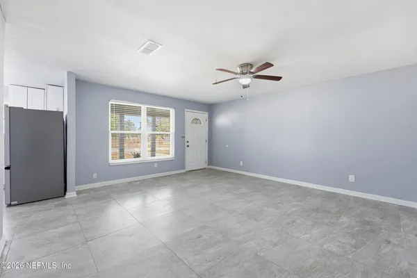 an empty room with chandelier fan and windows