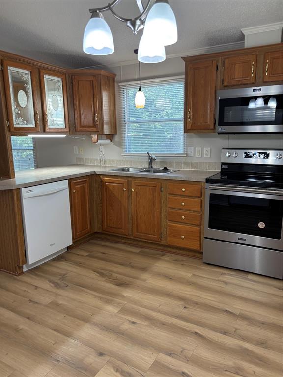 206 Holiday Rambler Drive Whitney, TX 76692 - Photo 8 of 28 Kitchen featuring wood-finish flooring, oak cabinetry, stainless steel range, stainless steel microwave, and a double basin sink