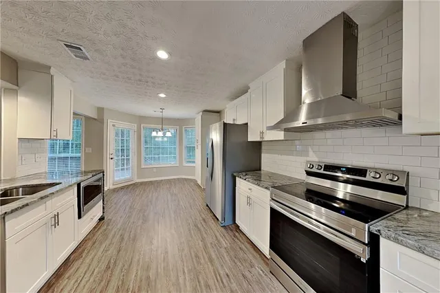 a kitchen with stainless steel appliances a stove a sink a refrigerator wooden floor and cabinets