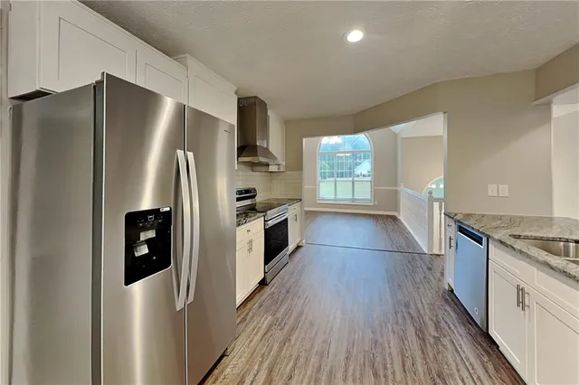 a kitchen with stainless steel appliances a refrigerator and wooden floor