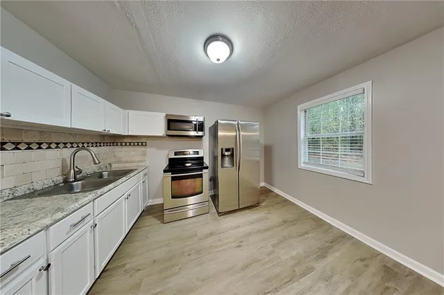 a kitchen with stainless steel appliances granite countertop a stove a sink and a refrigerator