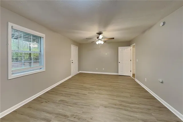 a view of an empty room with chandelier fan and wooden floor