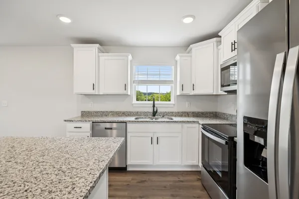 a kitchen with granite countertop white cabinets and stainless steel appliances