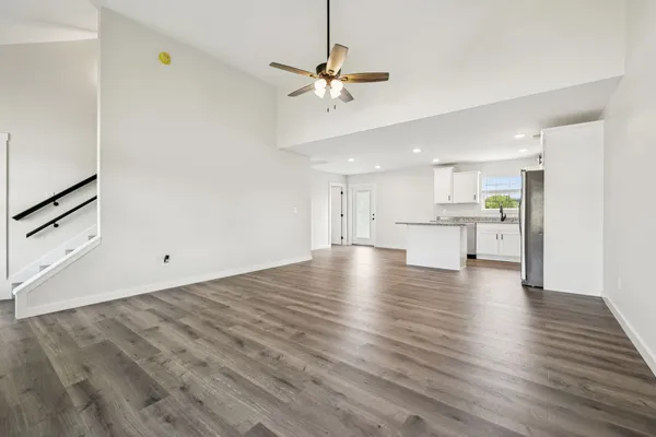 a view of an empty room with wooden floor ceiling fan