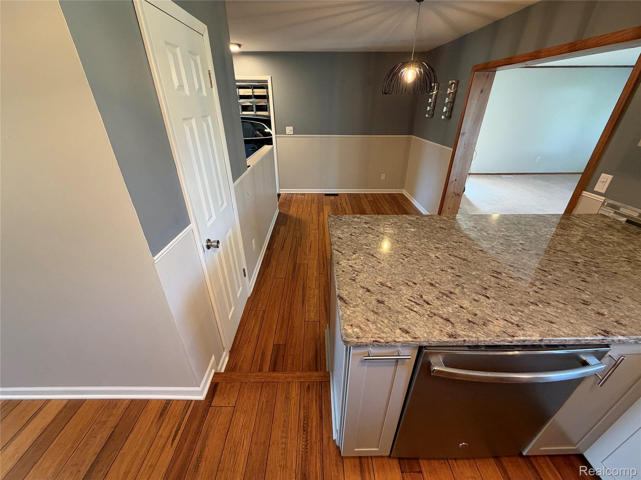 14629 Newburgh Road Livonia, MI 48154 - Photo 8 of 27 Wood-finish flooring throughout, with a kitchen island featuring a light-toned countertop and an integrated stainless steel dishwasher