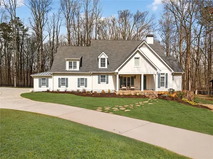 a front view of a house with a garden and trees