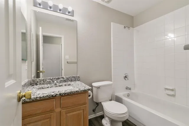 a bathroom with a granite countertop sink a toilet and a mirror