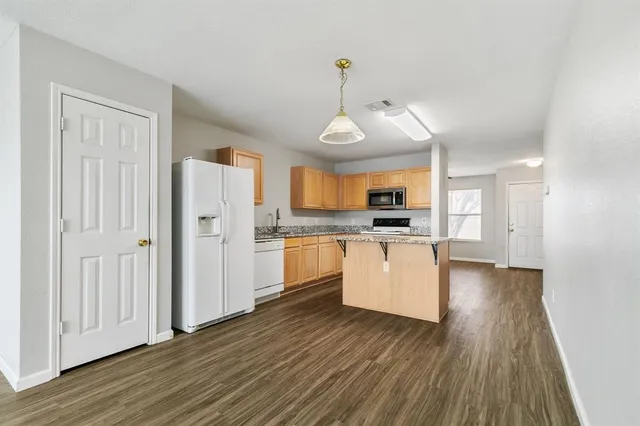 a view of an empty room with wooden floor and a ceiling fan