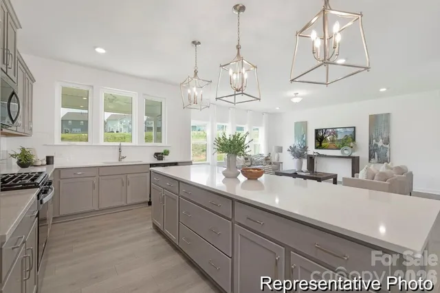 a large white kitchen with a large island oven a stove a sink a dining table and chairs