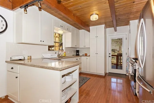 a kitchen with stainless steel appliances granite countertop a refrigerator a stove and a wooden floors