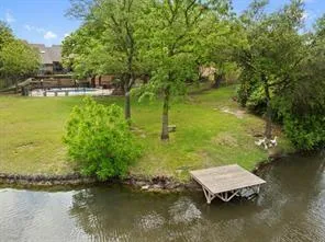 a wooden bench sitting in middle of a lake next to a yard