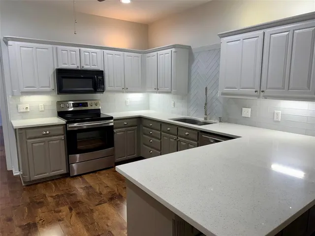 a kitchen with kitchen island granite countertop a sink dishwasher stove and refrigerator with wooden cabinets