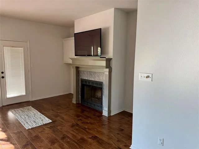 a view of an empty room with wooden floor and a fireplace