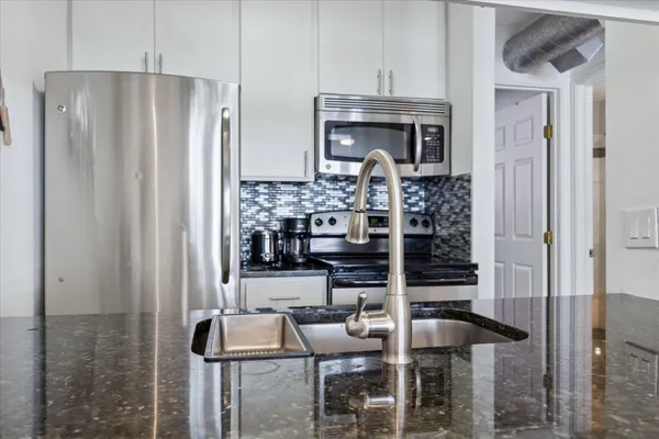 a kitchen with stainless steel appliances granite countertop a refrigerator and a stove top oven