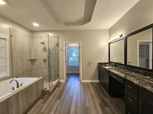 a spacious bathroom with a granite countertop tub sink shower and mirror