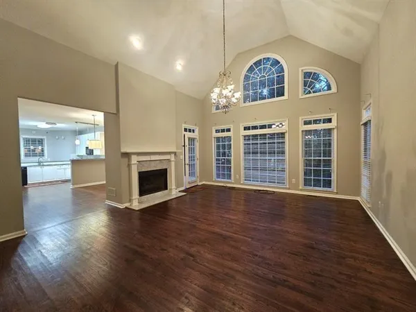 a view of an empty room with wooden floor fireplace and a window