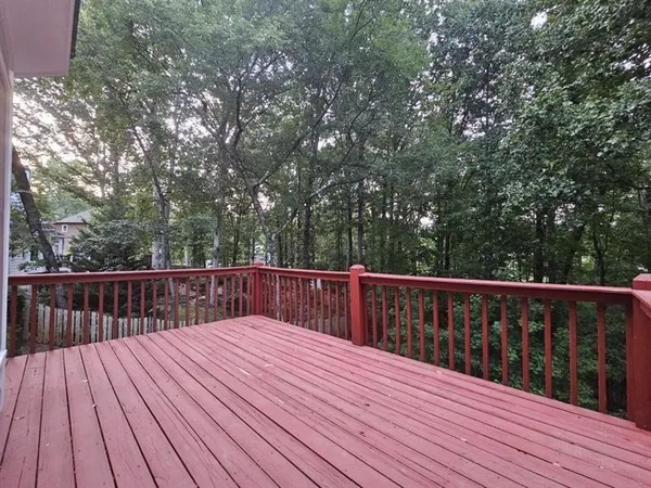 a balcony with wooden floor and trees in the back