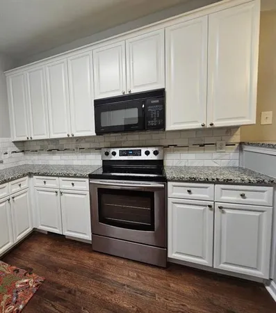 a kitchen with granite countertop white cabinets appliances and a sink
