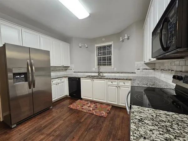 a kitchen with granite countertop stainless steel appliances a sink cabinets and wooden floor