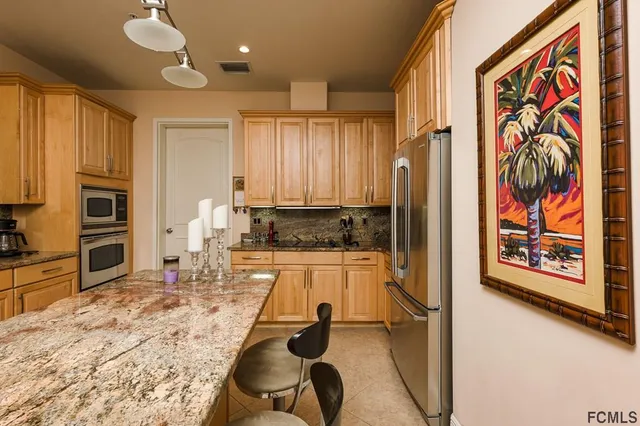 a kitchen with stainless steel appliances kitchen island granite countertop a refrigerator and a stove top oven