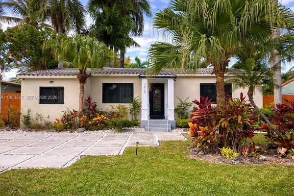a front view of a house with a yard and potted plants
