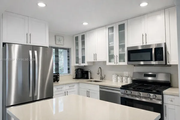 a kitchen with stainless steel appliances granite countertop a refrigerator stove top oven and sink