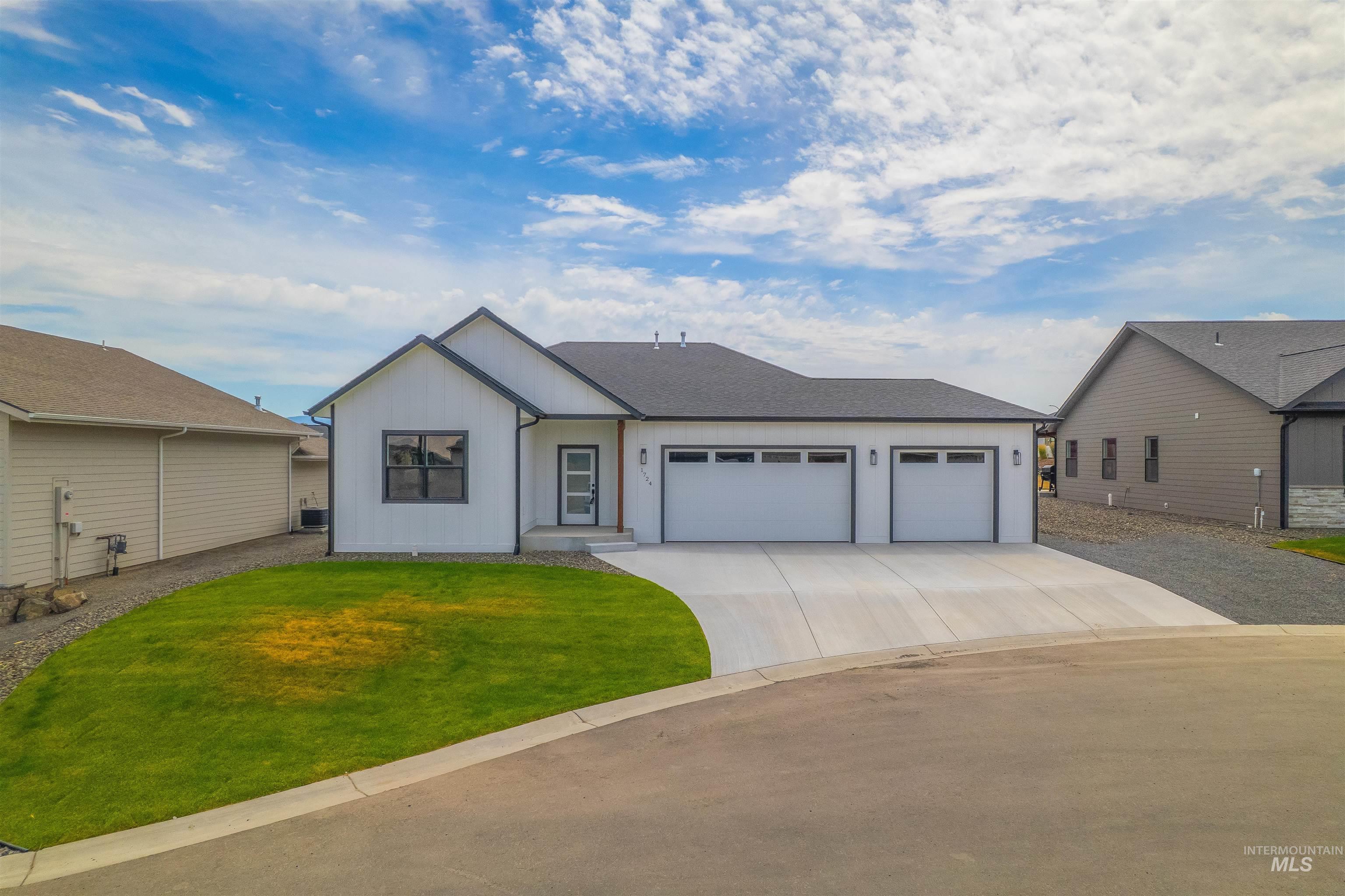 View of front facade featuring concrete driveway, a garage, and a front lawn