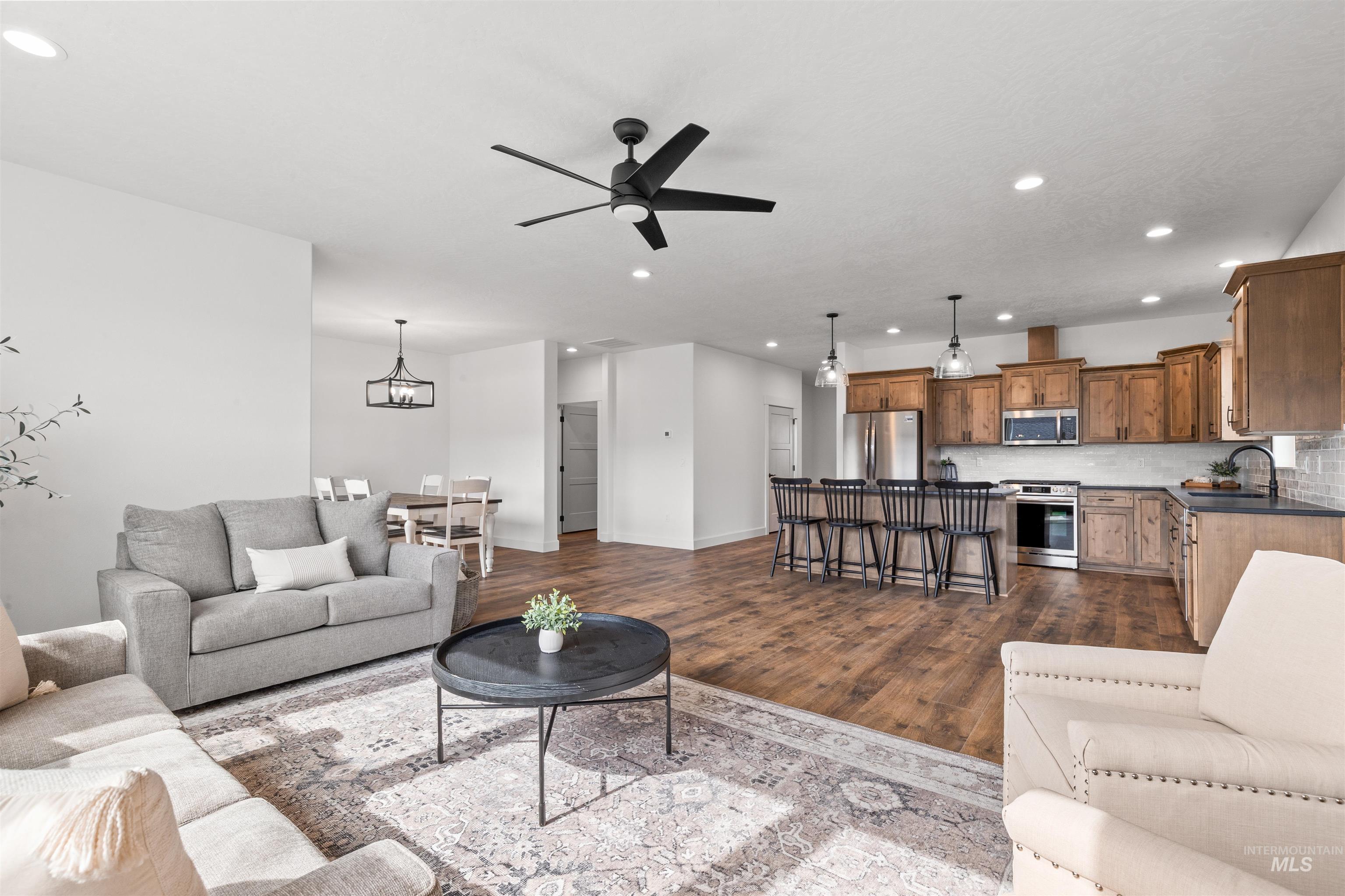 Living area with recessed lighting, ceiling fan, dark wood-type flooring, and a chandelier