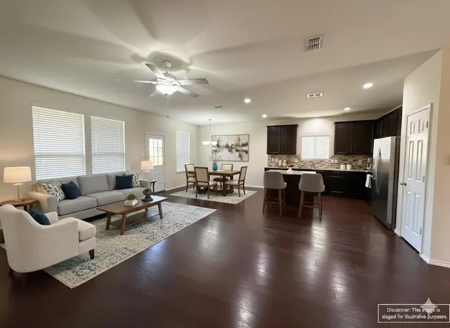 a living room with couches and kitchen view with wooden floor