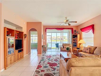 a living room with furniture a flat screen tv and floor to ceiling window