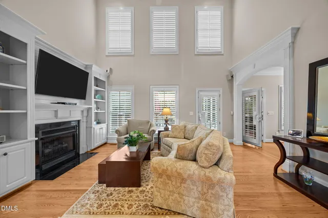 a living room with furniture a fireplace flat screen tv and windows