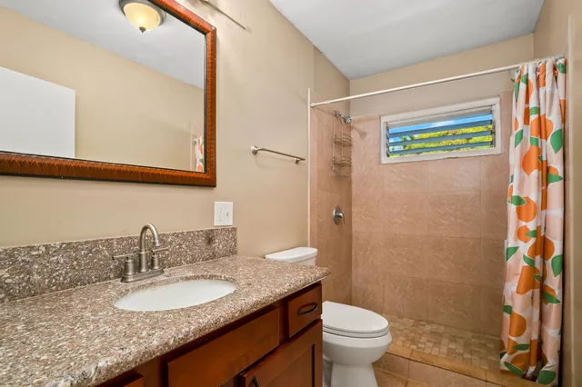 a bathroom with a granite countertop sink a toilet and a mirror