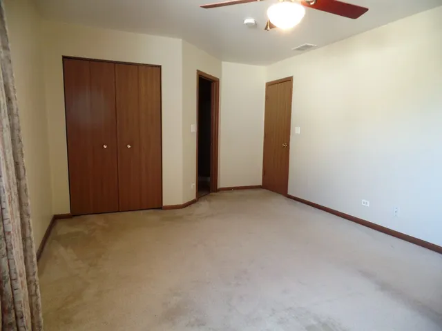 an empty room with closet and chandelier fan