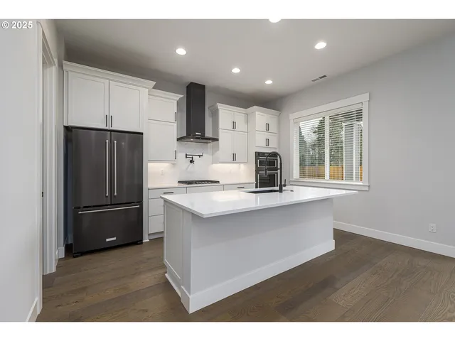 a kitchen with stainless steel appliances kitchen island granite countertop a refrigerator a sink a stove a microwave and wooden cabinets