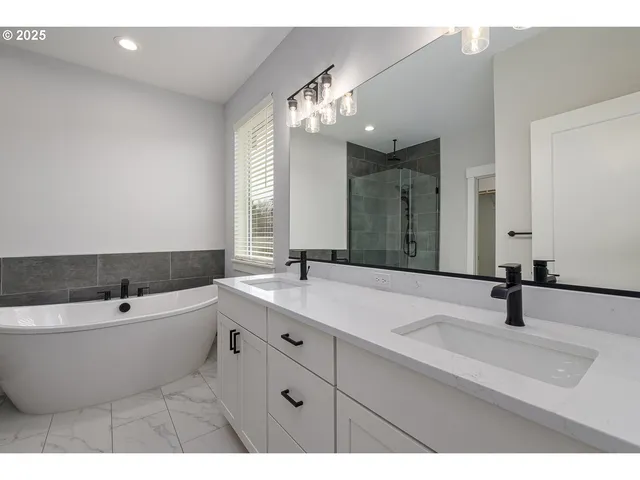 a bathroom with a bathtub a double vanity sink and mirror