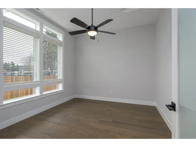 a view of an empty room with a window and wooden floor