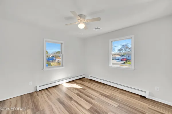 a view of an empty room with window and wooden floor
