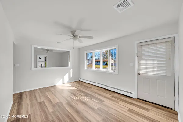 a view of an empty room with wooden floor and a window