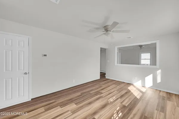 a big room with wooden floor closet and windows
