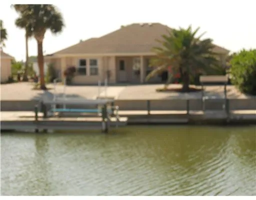 a view of a swimming pool with a lawn chairs under palm trees